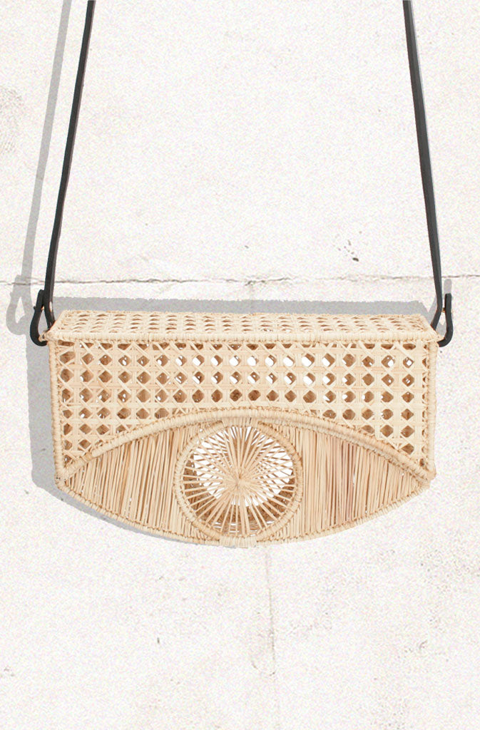 Ojo BagHard Shaped BagHardshell bag in natural beige with long black leather strap. Eye shaped design in the centre of the bag. Flip top with magnetic button closure.This bag is part of MGlobalistinaOjo BagGlobalistina