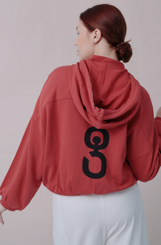 Delin Crop HoodieHoodieCozy crop hoodie, brick red, featuring an additional rib collar in the front for extra comfort and warmth and a big 'g' print across the back. The lowered shoulder sGlobalistinaDelin Crop HoodieGlobalistina